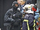 Francouzsk� policista ze z�sahov� jednotky a hasi�i nedaleko domu, ve kter�m se