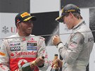 SD�LEN� RADOST. Lewis Hamilton sprchuje v�t�ze Velk� ceny ��ny Niko Rosberga.