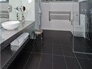V koupelně byly použity černé velkoformátové obklady v kombinaci s nerezovou V koupelně byly použity černé velkoformátové obklady v kombinaci s nerezovou
