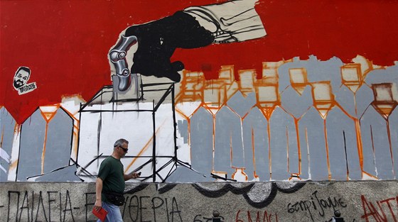 �ek proch�z� v At�n�ch kolem opu�t�n� budovy s grafitti odkazuj�c�m na