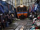 VLAK NA TR�I�TI. Thaj�tí trhovci sklízejí své zbo�í p�ed projí�d�jícím vlakem....