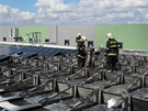 Po��r fotovoltaick�ch panel� na st�e�e skladu ve V�echromech.