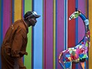 �ezbá� Jackson Mbatha s je�t� nedokon�enou velkou hra�kou �irafy p�ed malovanou...