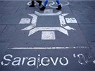 People walk past the logo of the Winter Olympics in Sarajevo, painted on the... People walk past the logo of the Winter Olympics in Sarajevo, painted on the...