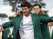 Loňský šampion Adam Scott (vzadu) obléká do zeleného saka pro vítěze golfového... Loňský šampion Adam Scott (vzadu) obléká do zeleného saka pro vítěze golfového...